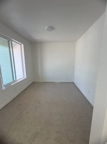 Recessed lighting, neutral carpet, and a large window