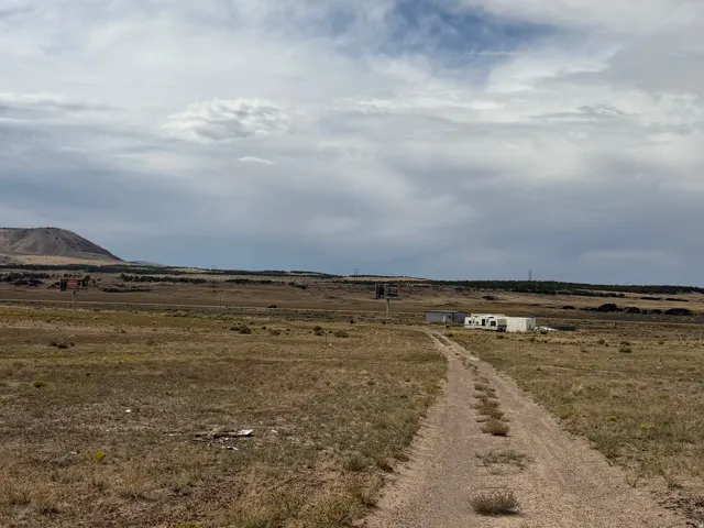 Expansive land with a gravel driveway, featuring distant mountain formations and natural terrain