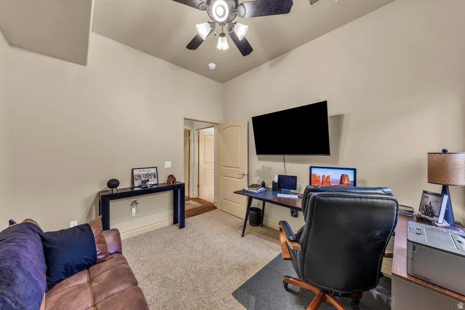 Versatile bonus room with vaulted ceiling, ceiling fan with integrated lighting, wall-mounted flat-screen TV, and neutral carpet flooring