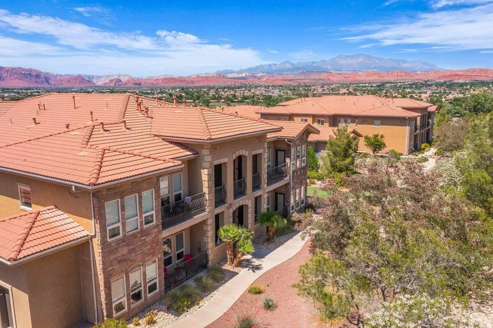 Terracotta tile roofs, stucco exterior, stone facade accents, private balconies, and surrounding natural desert landscaping