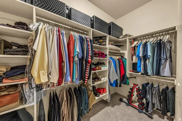 Custom closet system featuring multiple hanging rods, integrated shelving, and carpet flooring