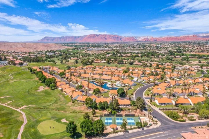 Residential community featuring terracotta-roofed homes, mature palm trees, and manicured green spaces