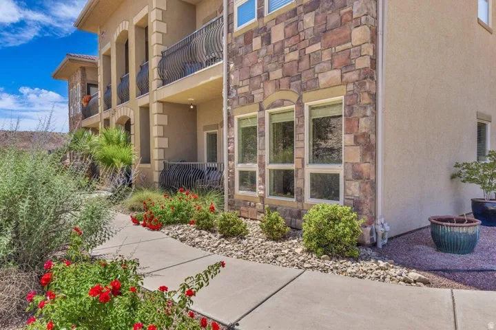 Stone and stucco exterior detailing, arched window frames, multiple private balconies with wrought iron railings, and mature landscaping