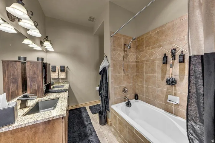 Spa-inspired master bathroom featuring dual vanities with marble-look countertops, wood-finish cabinetry, and polished nickel fixtures