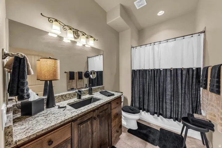 Granite-finish countertop with an undermount sink, wood-finish cabinetry, and a full-width wall mirror