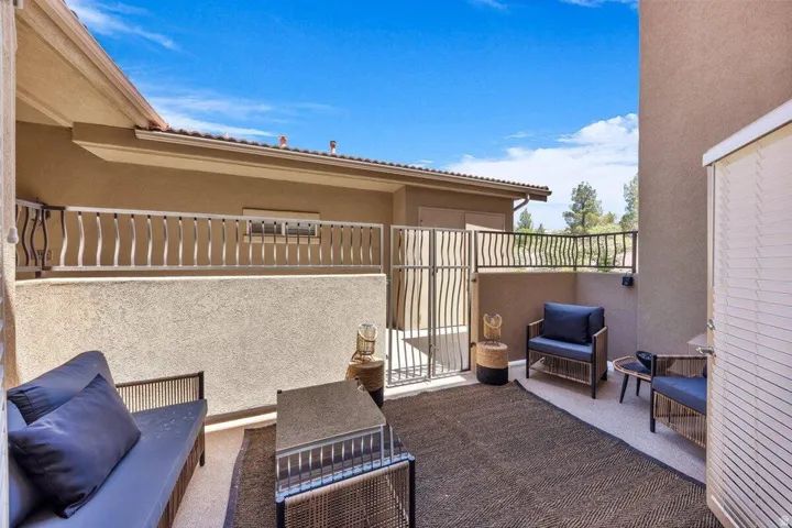 Private patio area with stucco walls, tile roofing, and a decorative metal railing