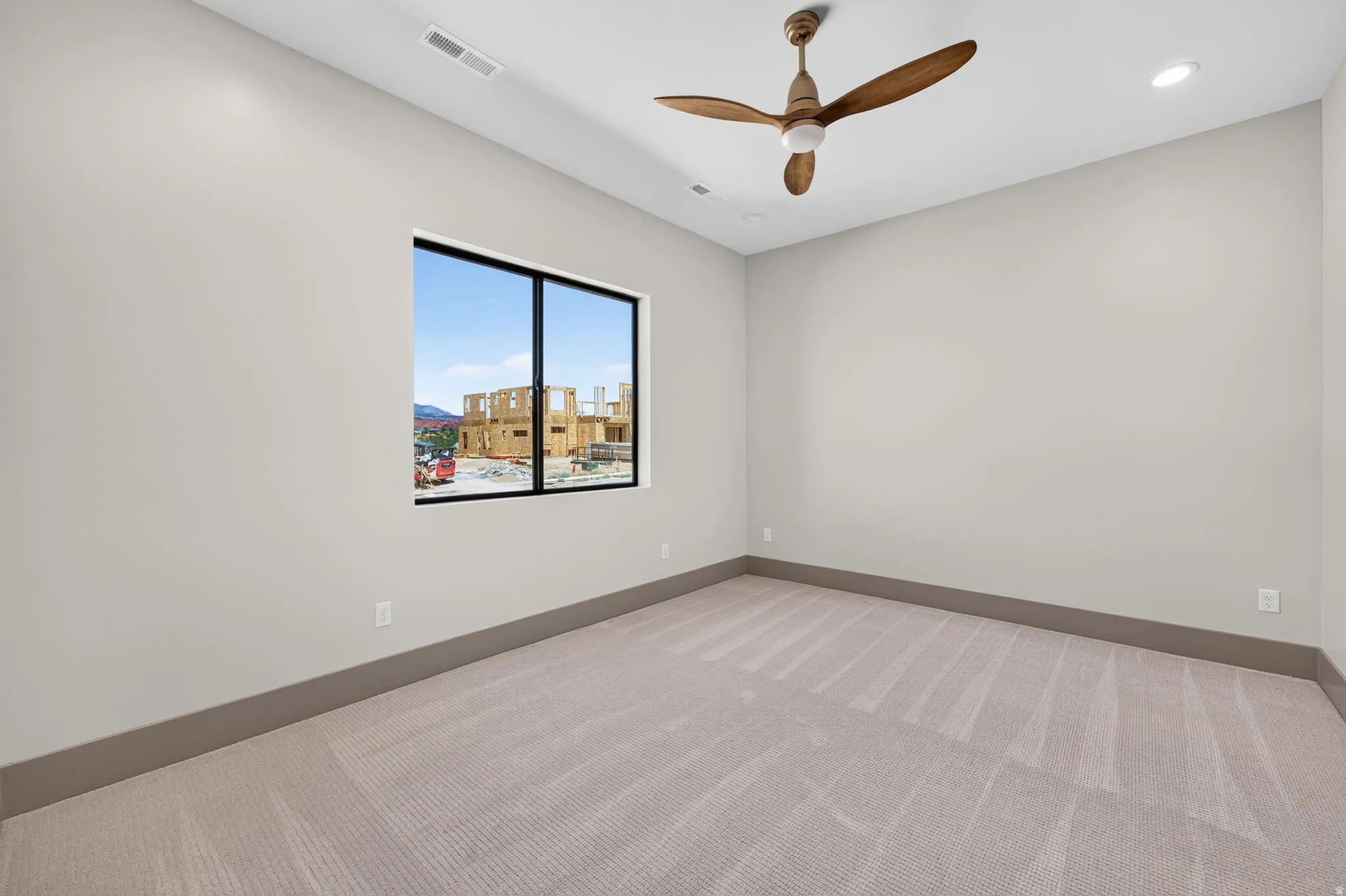Recessed lighting, contemporary ceiling fan, large window with black trim, and neutral-toned wall paint