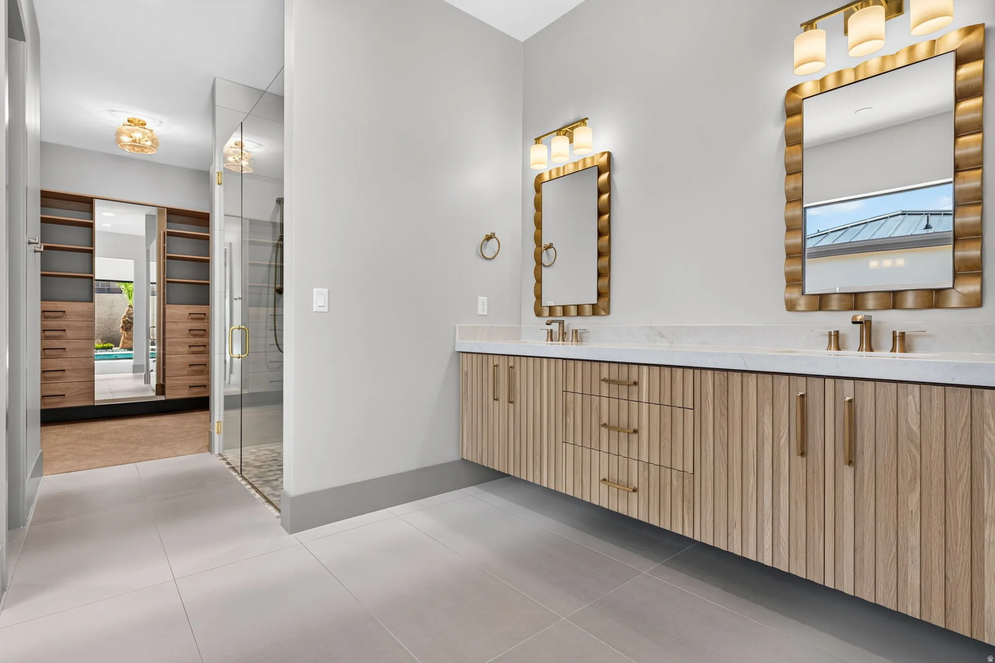 Dual vanity with light wood-finish cabinetry, white countertop, and gold-toned fixtures