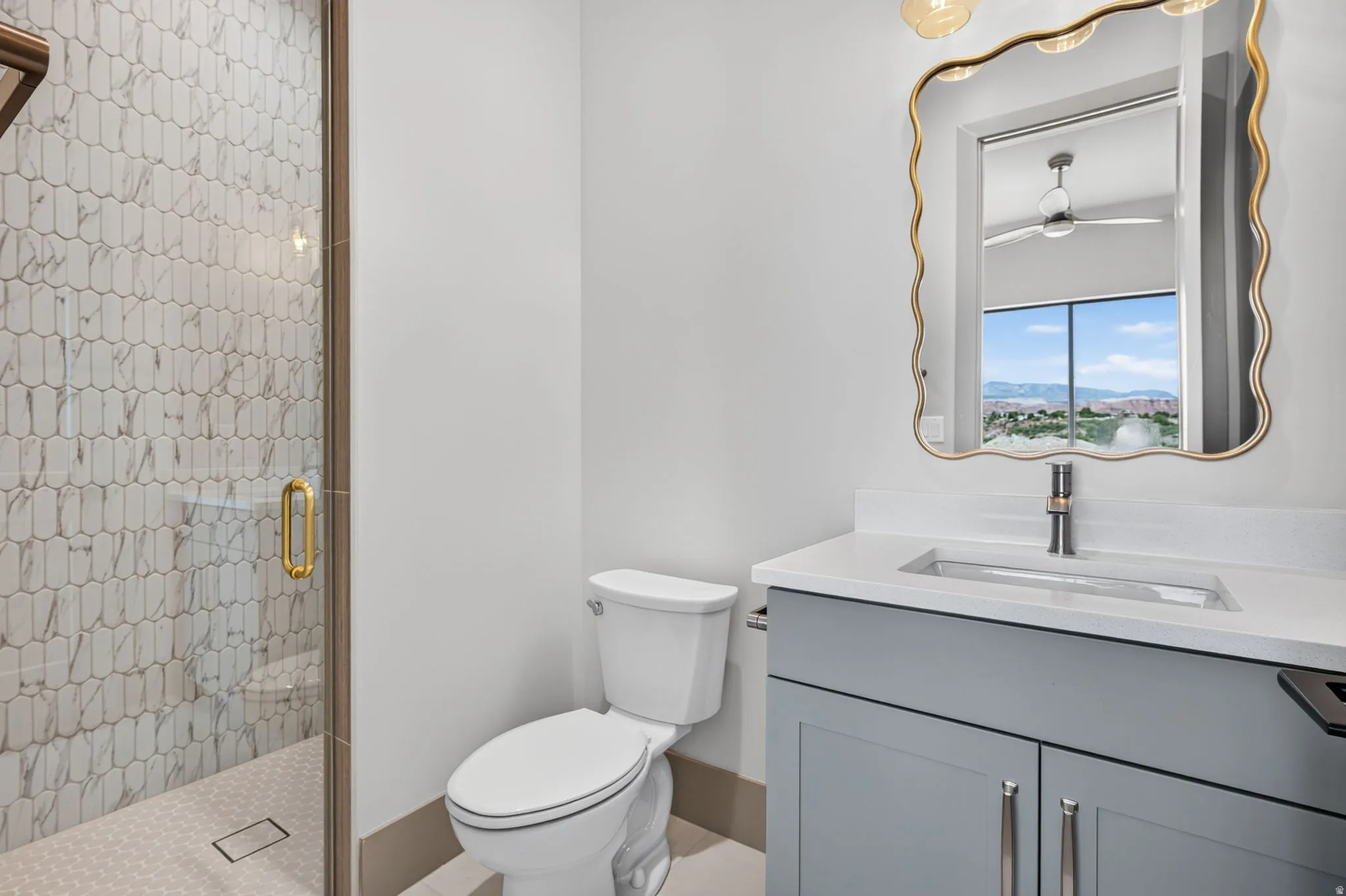 Glass-enclosed shower with elongated hexagon tile surround, wood-finish trim, and gold-tone hardware