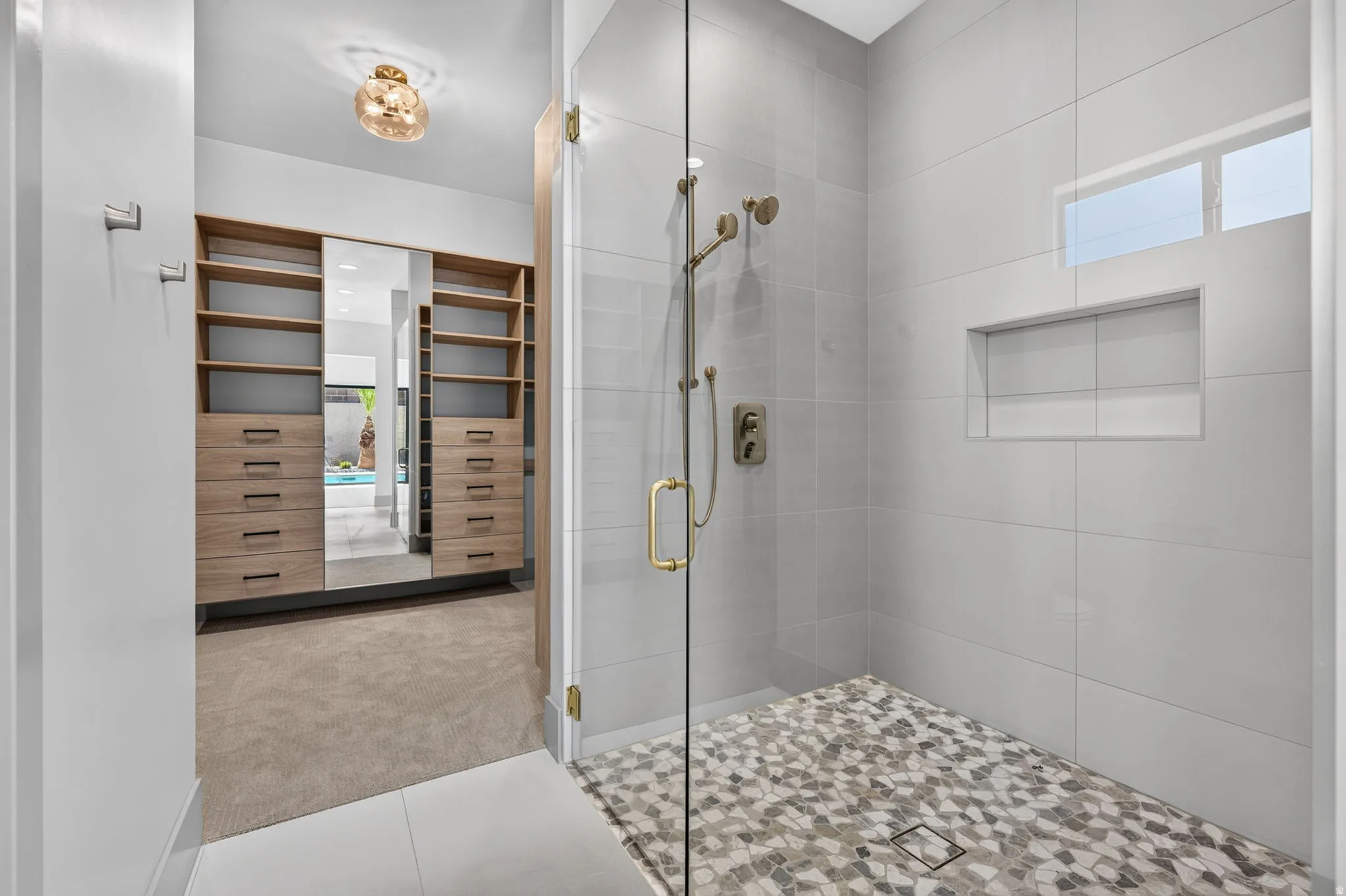 Walk-in shower with full-height glass enclosure, mosaic tile shower floor, and a built-in shower niche