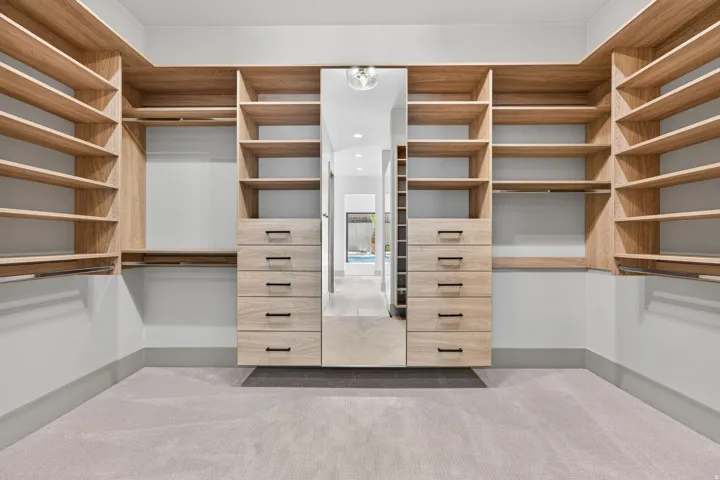 Built-in closet system featuring wood-finish shelving, multiple drawers with dark hardware, and integrated hanging rods