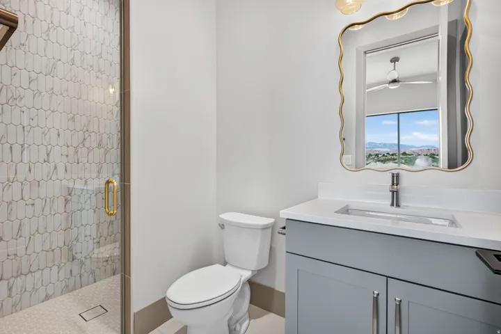 Glass-enclosed shower with elongated hexagon tile surround, wood-finish trim, and gold-tone hardware
