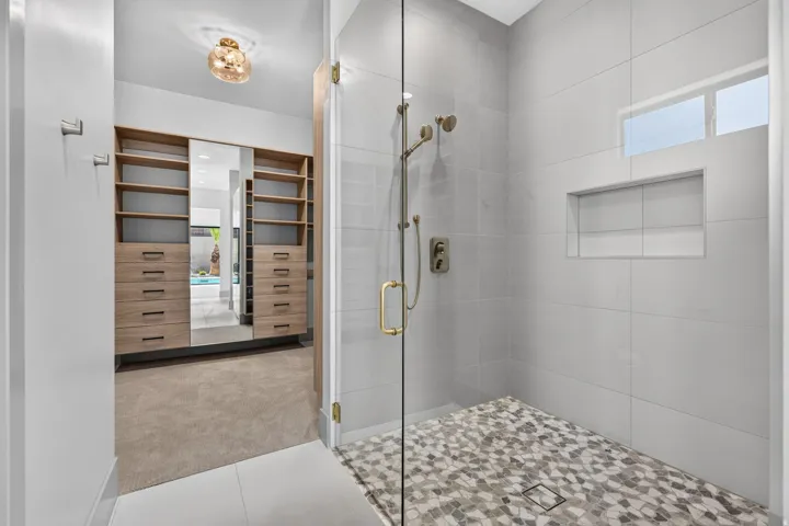 Walk-in shower with full-height glass enclosure, mosaic tile shower floor, and a built-in shower niche