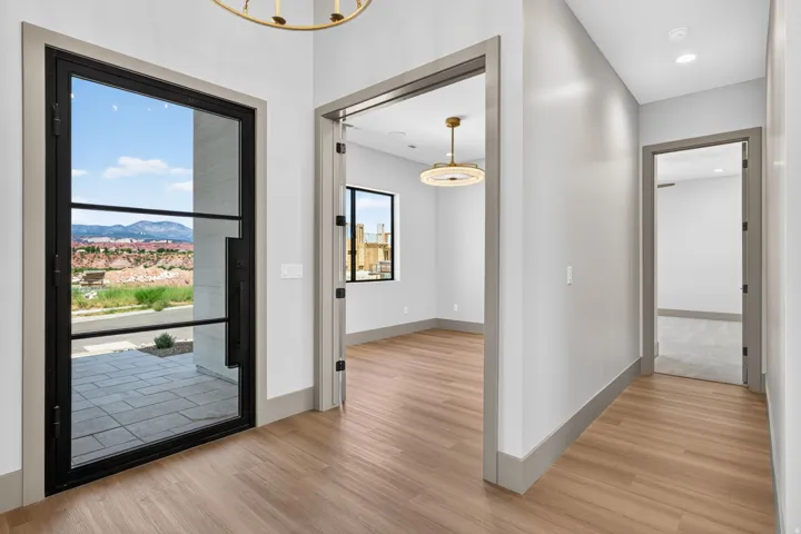 Wood-finish flooring throughout, modern entry door with black framing, recessed lighting, and contemporary ceiling light fixture