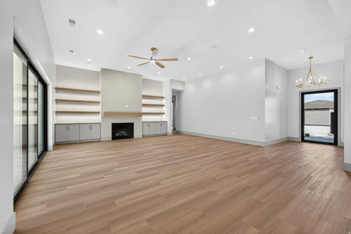 Wood-finish flooring throughout, featuring a built-in fireplace with a mantel, open shelving, and cabinet storage
