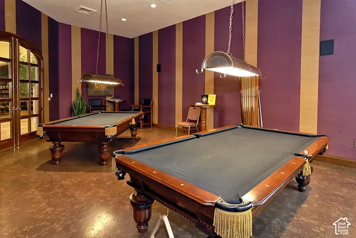 Elegant recreation room featuring two professional-grade pool tables with wood-finish frames and slate playing surfaces, complemented by pendant lighting with brass accents