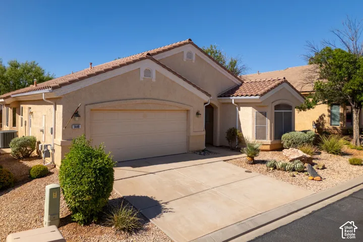 Southwestern-style residence featuring a two-car garage with paneled door, terracotta tile roof, and stucco exterior