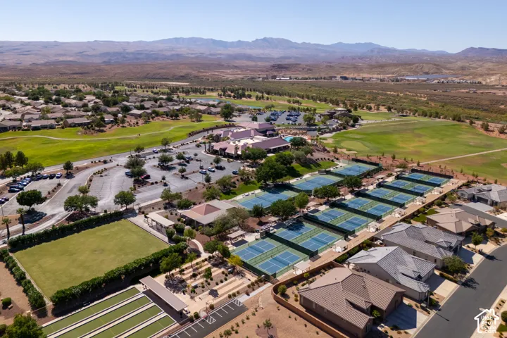 Community featuring multiple tennis courts, a large golf course, a manicured green space, paved parking areas, and built structures