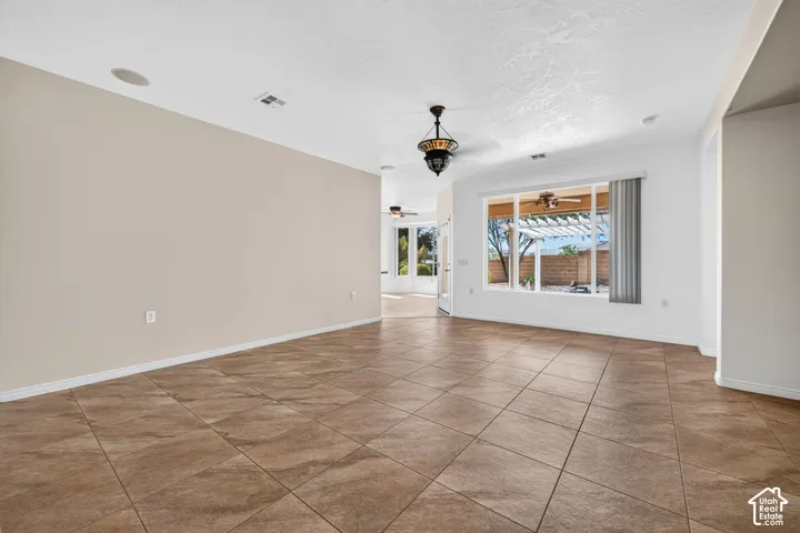 Spacious open-concept living area featuring diagonal wood-finish tile flooring, recessed ceiling lighting, and abundant natural light from expansive windows