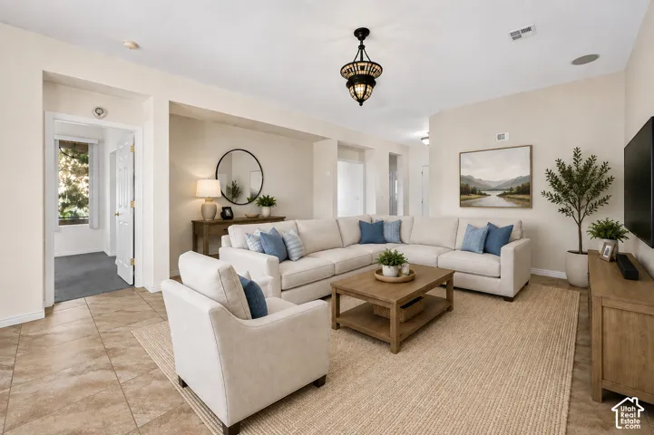 Spacious living area featuring tile flooring, a decorative overhead light fixture, and neutral wall tones