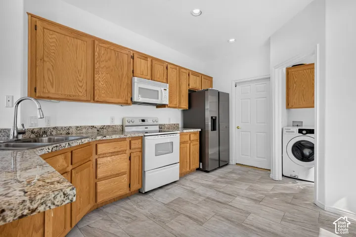 Spacious kitchen featuring wood cabinetry, granite-style countertops, stainless steel appliances including a side-by-side refrigerator and gas range, and plank-style flooring