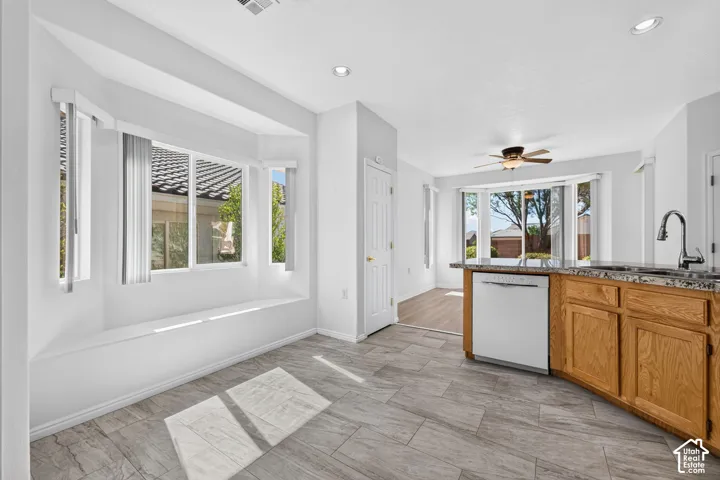 Bay window with integrated seating, recessed lighting, tile flooring, wood-finish cabinetry, and a built-in dishwasher