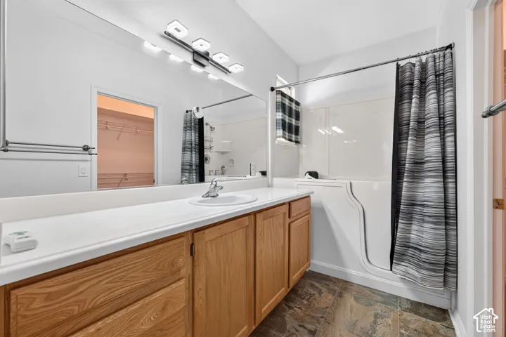 Vanity with wood-finish cabinetry, white countertop, and integrated sink