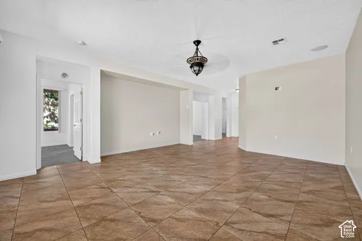 Spacious open floor plan with wood-finish tile flooring throughout, recessed ceiling lighting, and pendant fixture