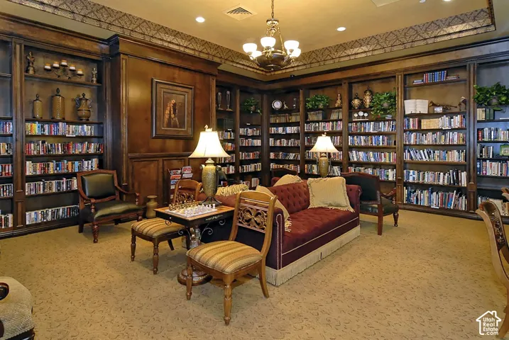 Sophisticated home library featuring floor-to-ceiling built-in cabinetry with glass-front shelving, rich wood paneling, and decorative crown molding