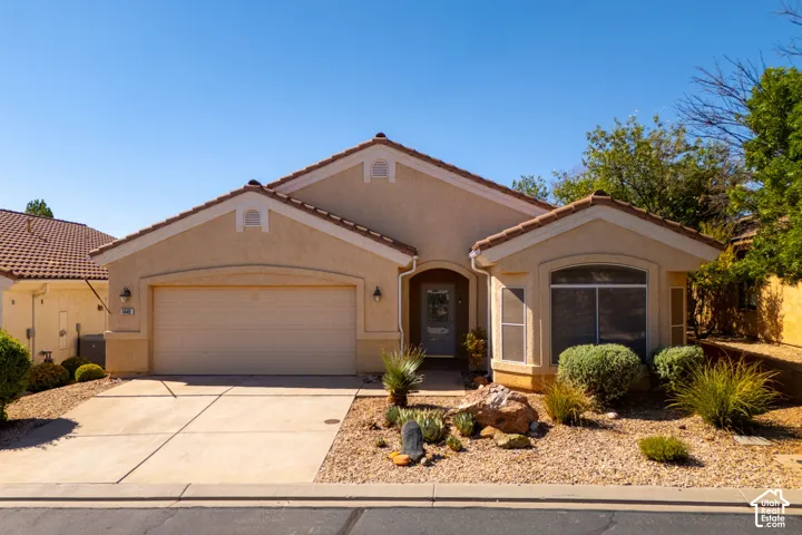 Stucco exterior with a tiled roof, integrated two-car garage, and a concrete driveway