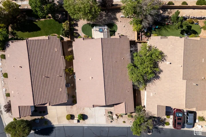 Aerial view showcasing three residences with clay tile roofing, concrete driveways, and mature landscaping throughout the properties