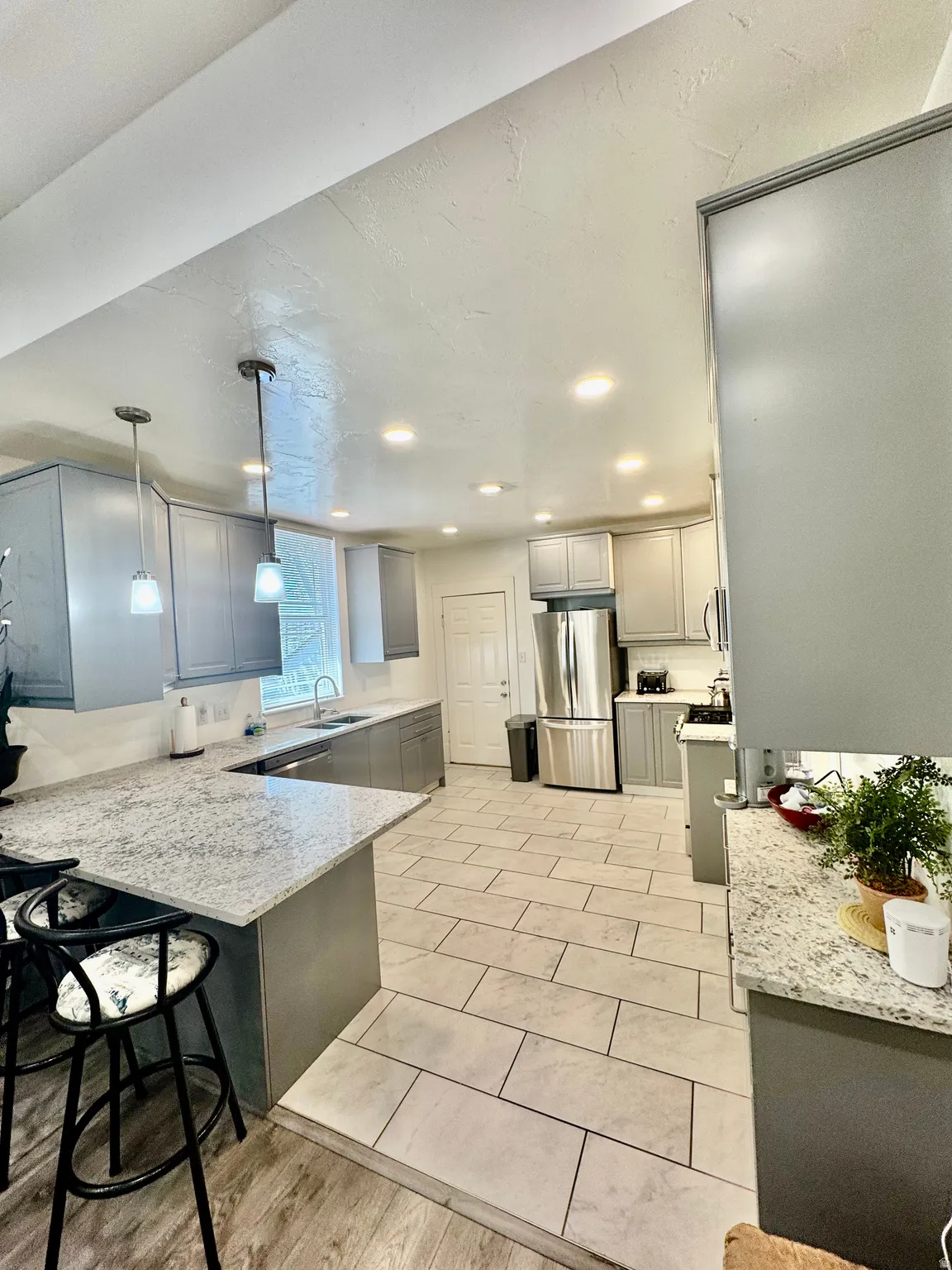 Modern kitchen featuring light gray cabinetry, granite countertops, and stainless steel appliances