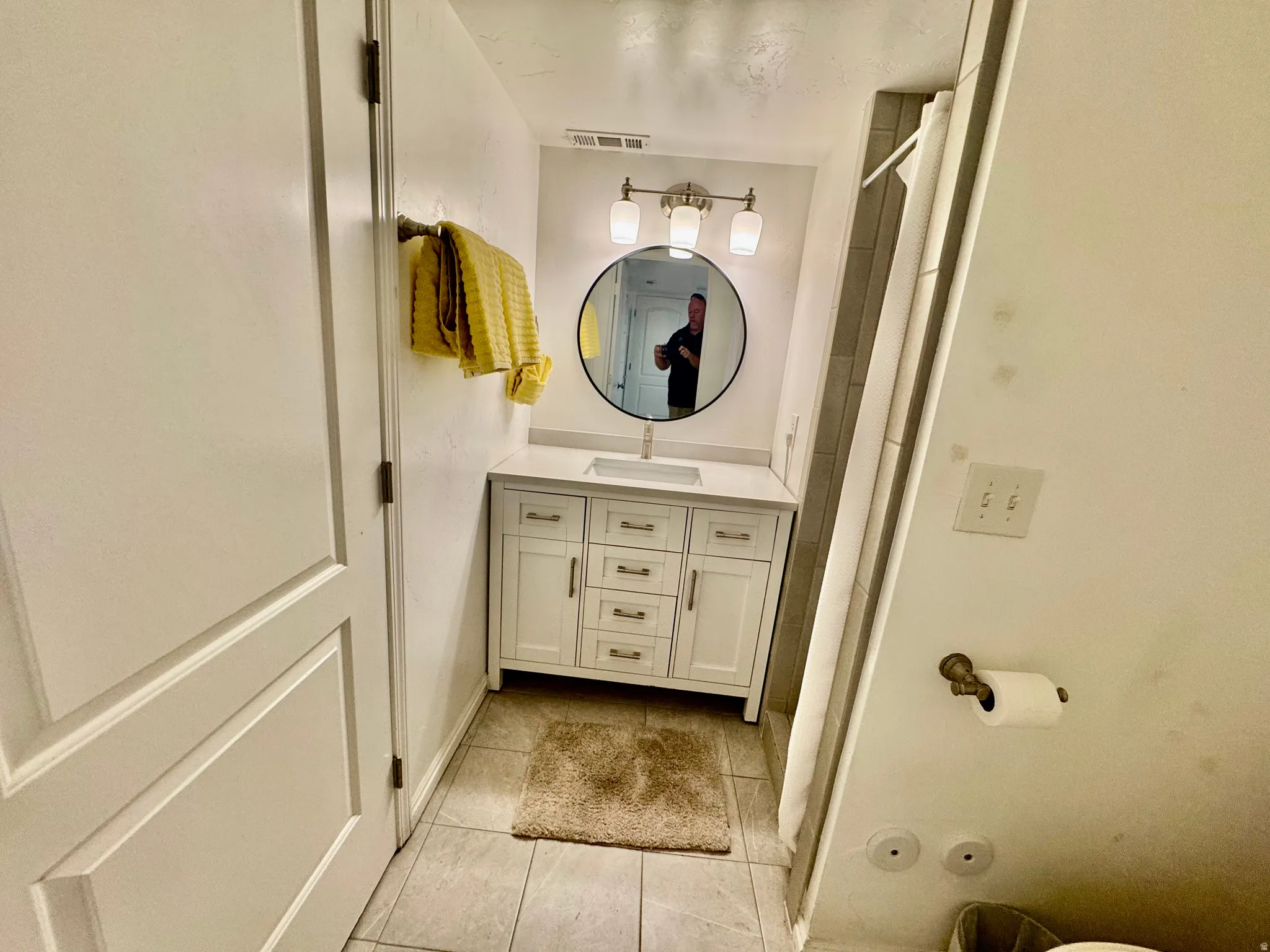Bathroom vanity featuring a white cabinet with brushed nickel hardware, a rectangular undermount sink, and a white countertop
