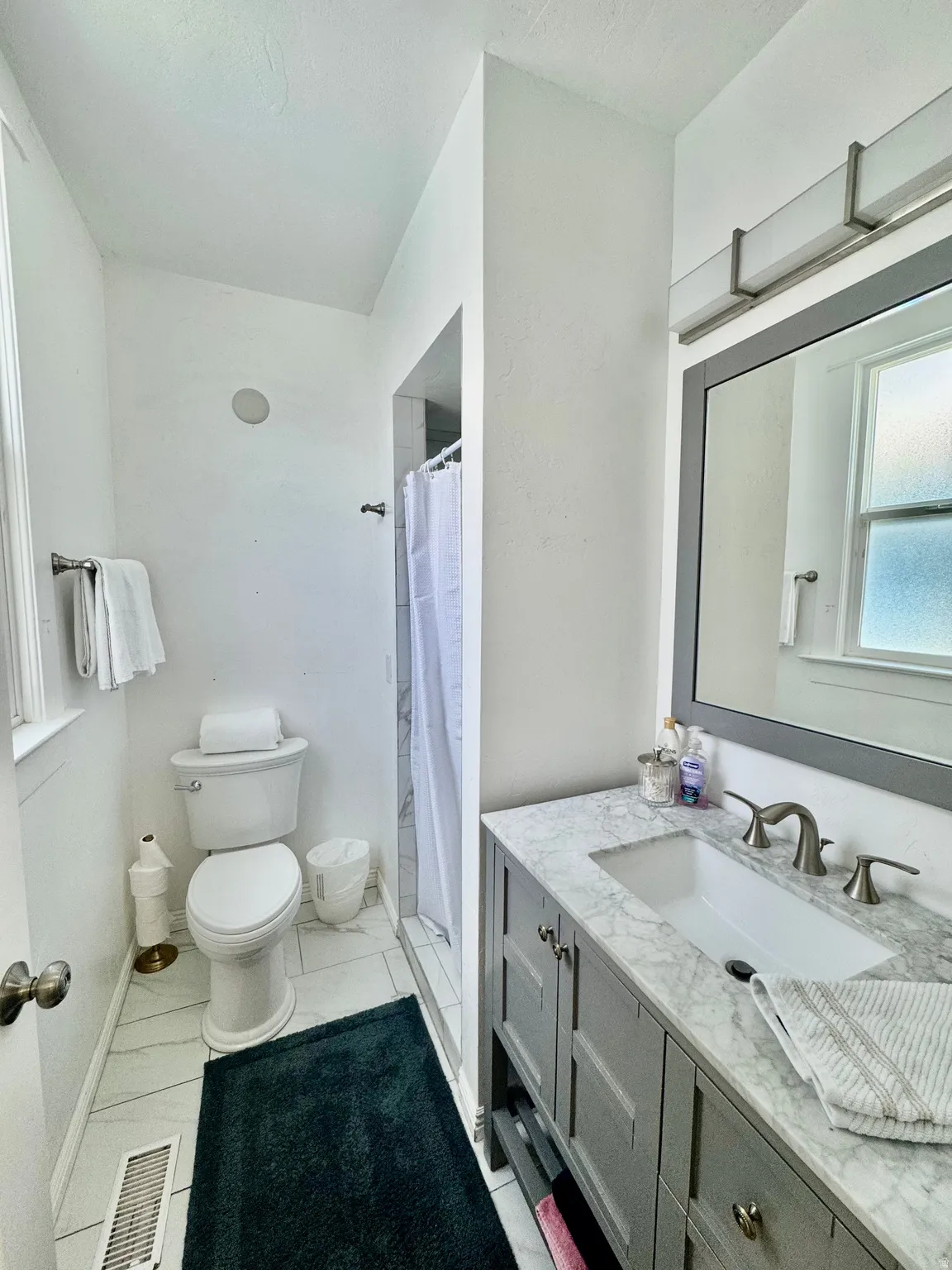 Bathroom featuring a gray vanity with a stone countertop and an undermount sink
