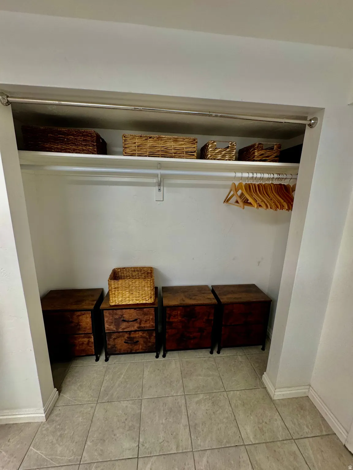 Integrated closet space featuring a clothing rod, upper shelving, and tiled flooring