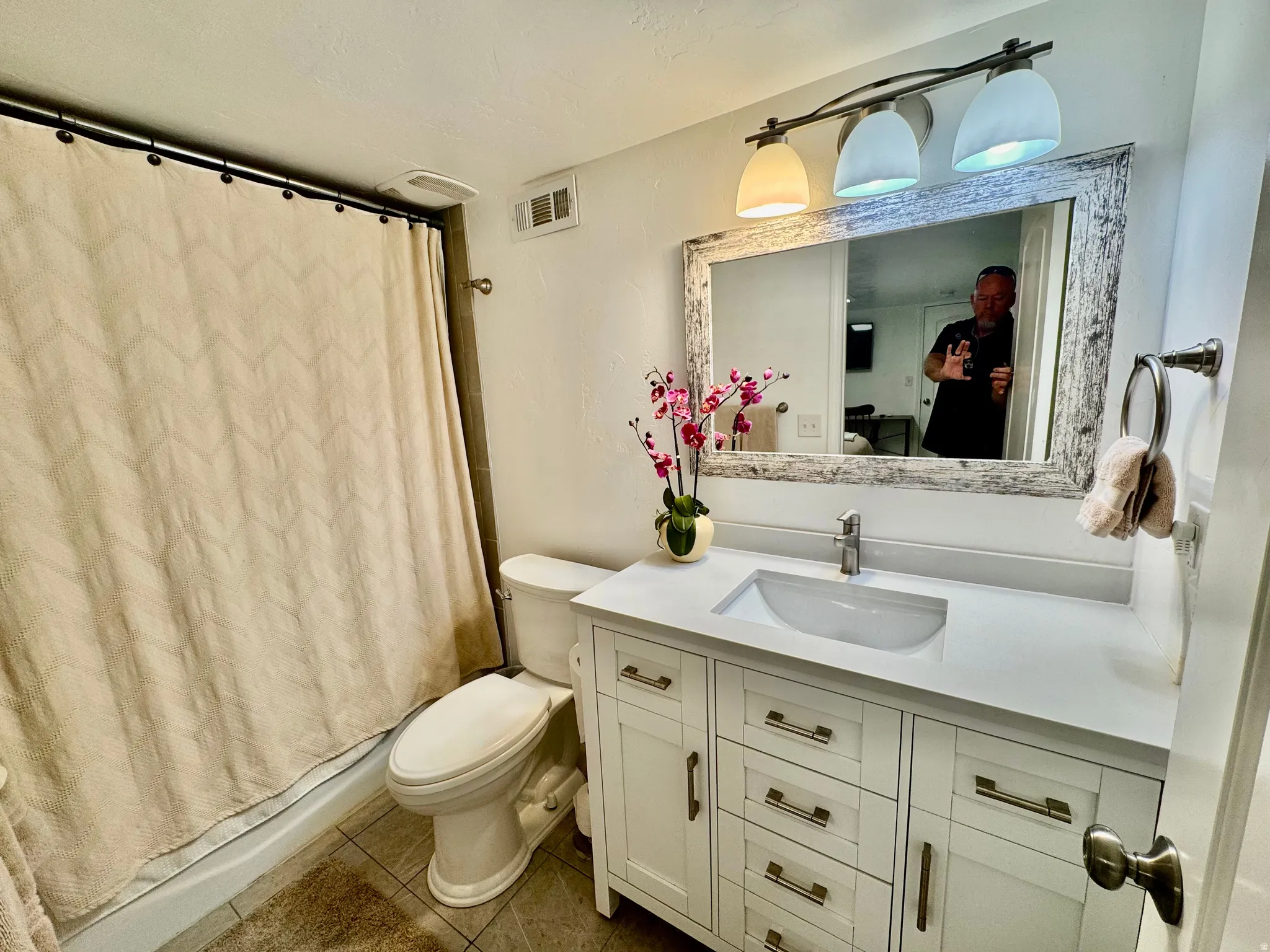 Bathroom featuring a white vanity with an integrated sink, brushed nickel faucet, and a distressed wood-frame mirror