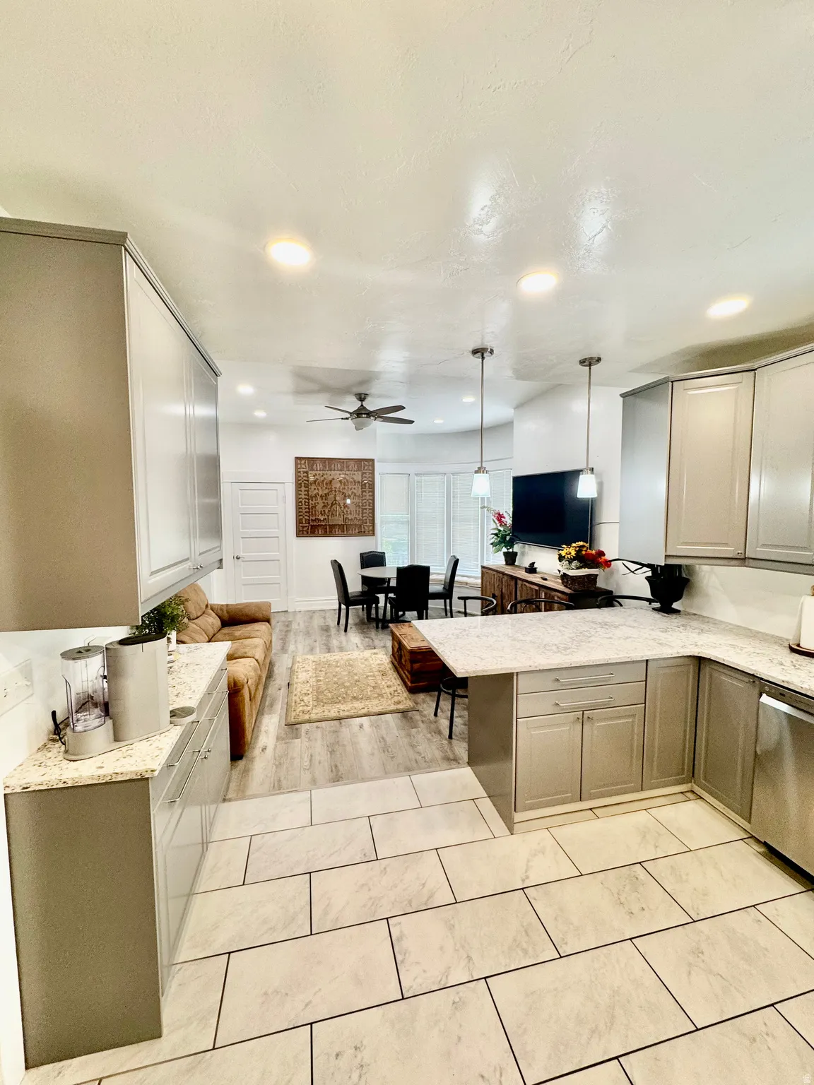 Open-concept living space featuring a kitchen with light-toned cabinetry and light-colored countertops, tile flooring, and recessed lighting