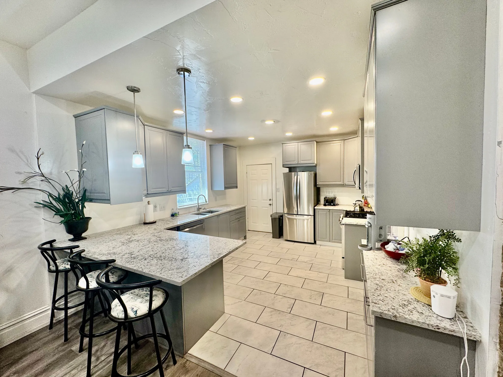 Contemporary kitchen featuring light gray cabinetry, light-toned stone countertops, and stainless steel appliances