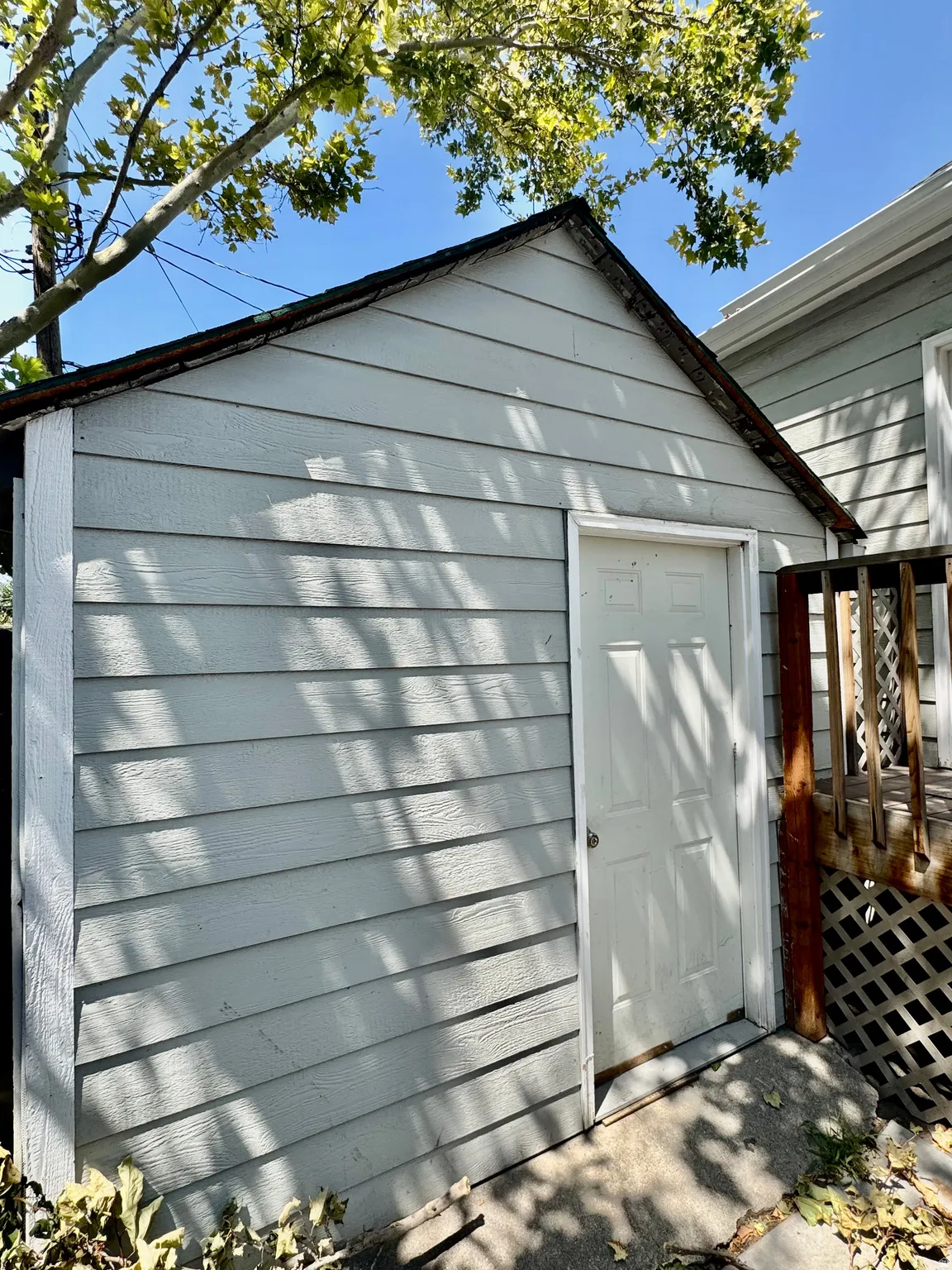 Storage shed with horizontal siding and a panel-style door, set on a concrete pad