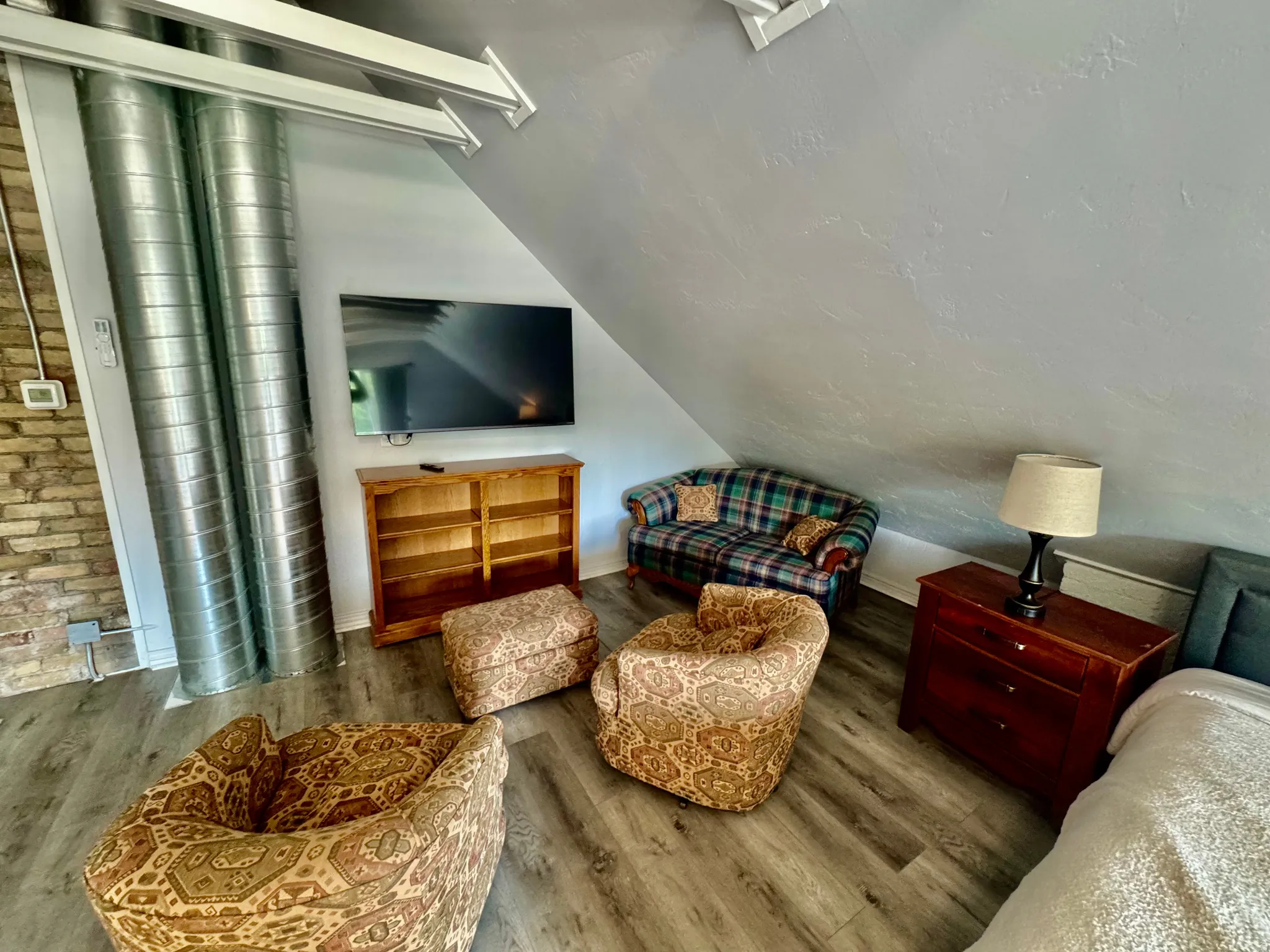 Attic living space featuring wood-finish flooring, exposed brick wall, and visible ductwork