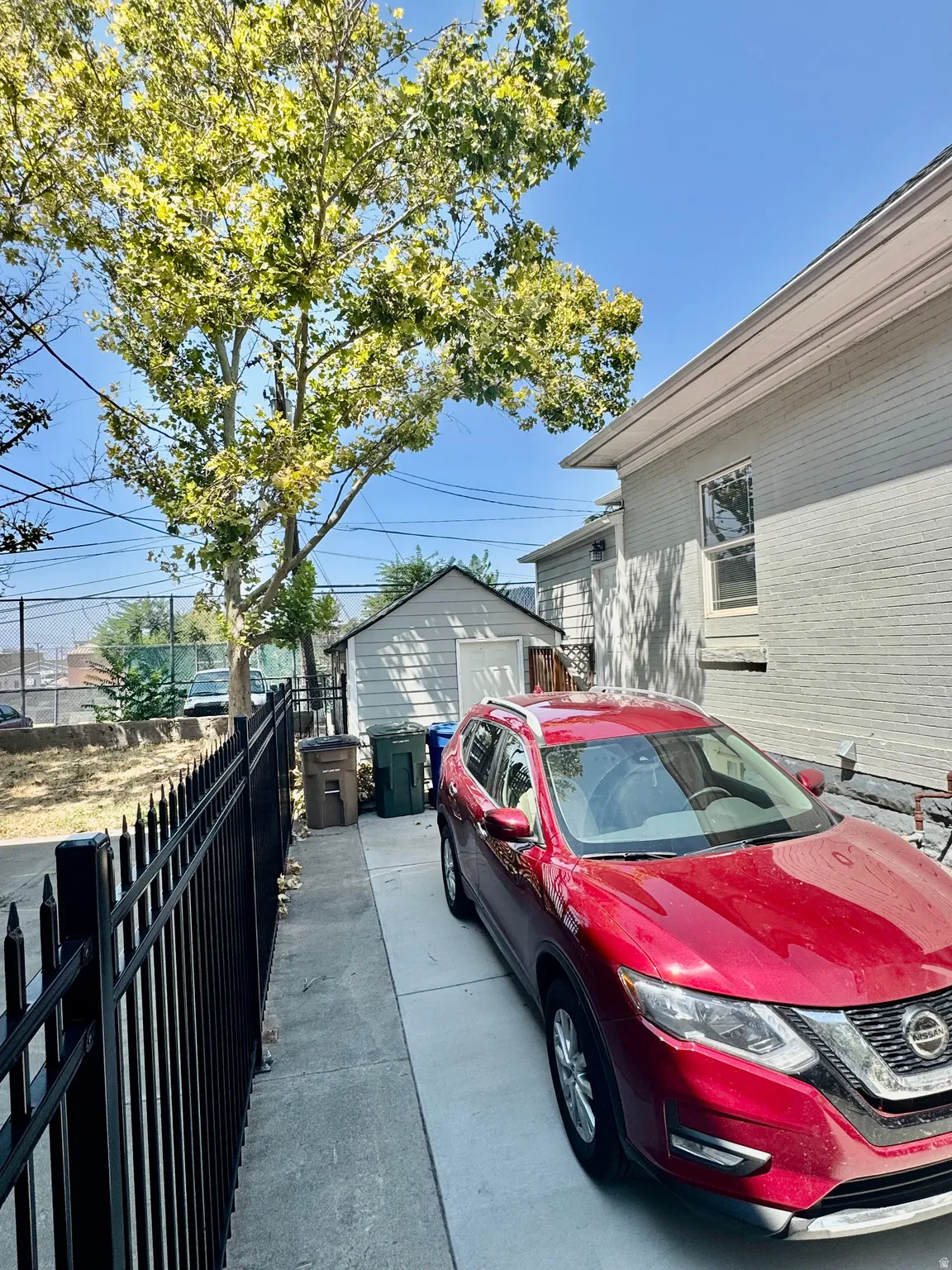 Paved driveway offering off-street parking, bordered by a black metal fence