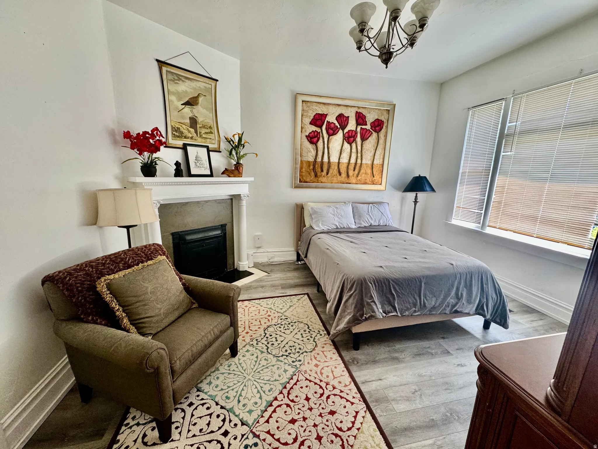 Bright room featuring wood-finish flooring, a decorative fireplace with a white mantel, and a window with blinds