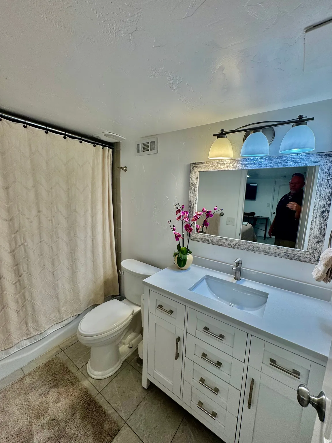 Bathroom featuring a white vanity with integrated sink, coordinating mirror, chrome fixtures, and tiled flooring