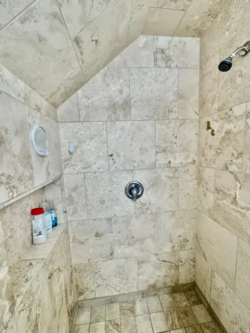 Fully tiled shower featuring a built-in bench, chrome shower head, and matching chrome fixture