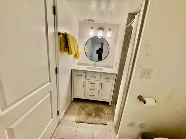Bathroom vanity featuring a white cabinet with brushed nickel hardware, a rectangular undermount sink, and a white countertop