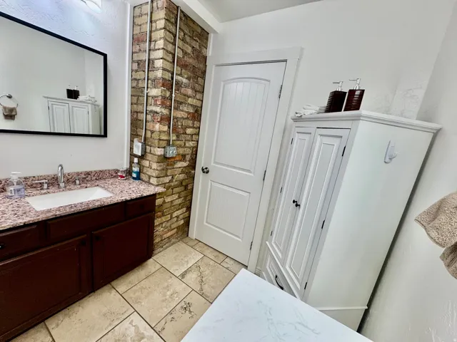 Vanity featuring a rectangular sink, granite countertop, and dark wood cabinetry