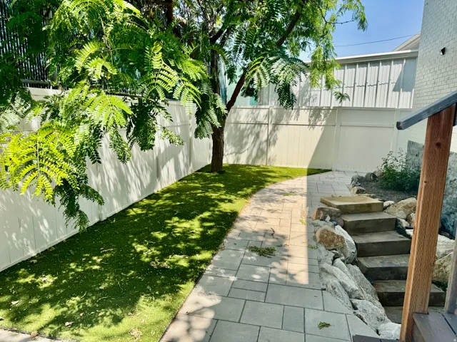 Expansive outdoor space featuring a paved walkway, artificial turf, and a natural stone staircase