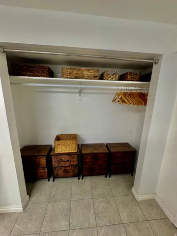 Integrated closet space featuring a clothing rod, upper shelving, and tiled flooring