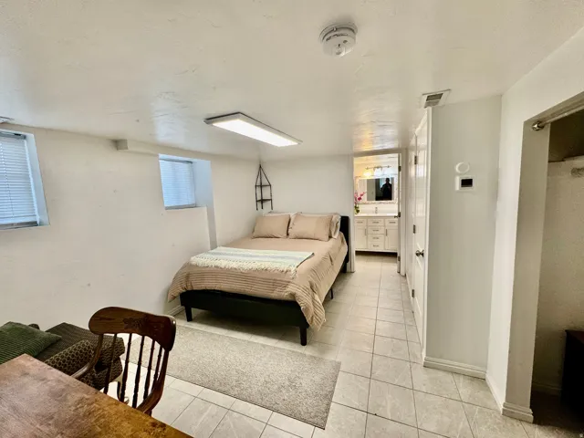 Bedroom featuring tile flooring, white walls, and two windows
