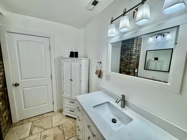 Bathroom vanity featuring a single integrated rectangular sink, a light-colored solid surface countertop, and a brushed nickel faucet